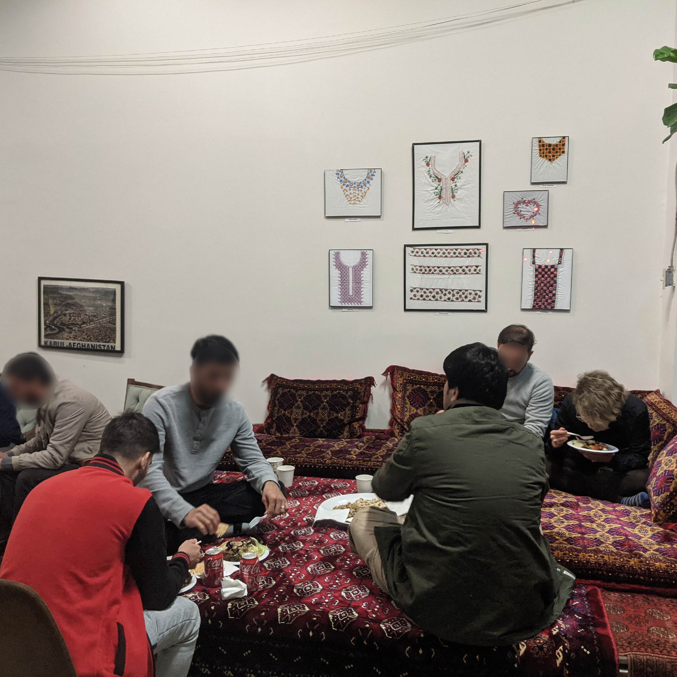 People are seated on read toshaks enjoying tea and snacks at the ACS anniversary open house.