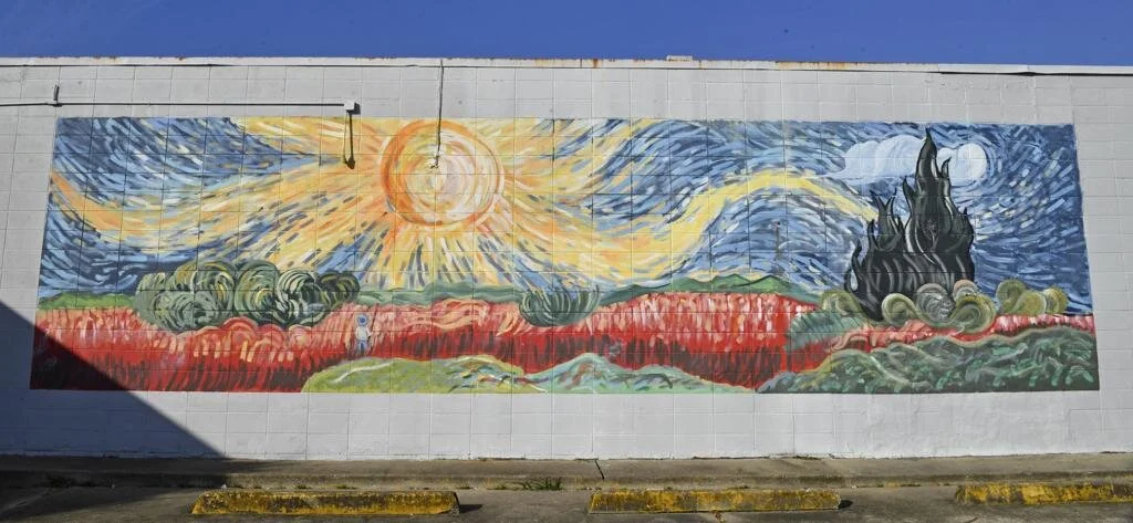 Colorful mural shows a radiant sun, swirling sky, and abstract landscape across a long wall.