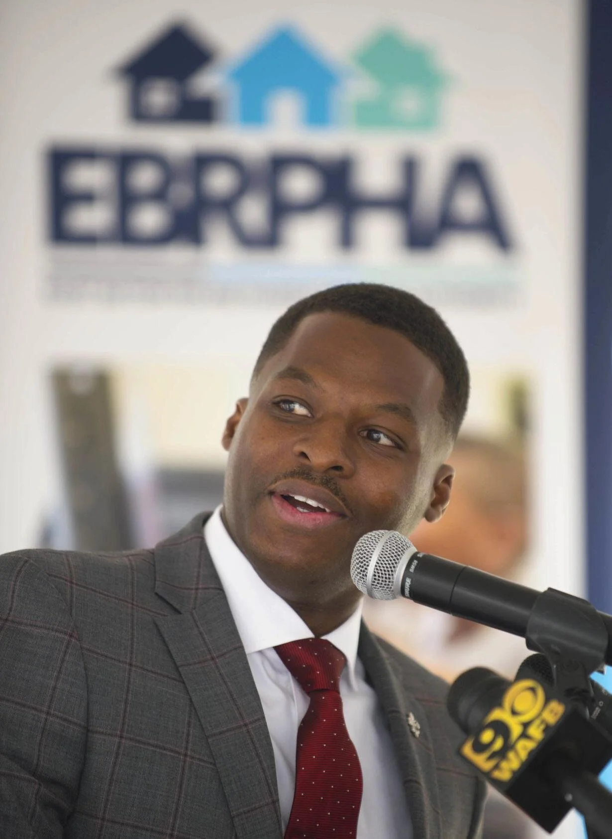 East Baton Rouge Parish Housing Authority CEO J. Wesley Daniels talking on a microphone with EBRPHA logo in the background
