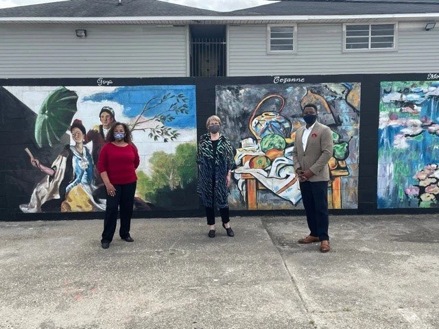 Four people standing in front of beautiful mural.