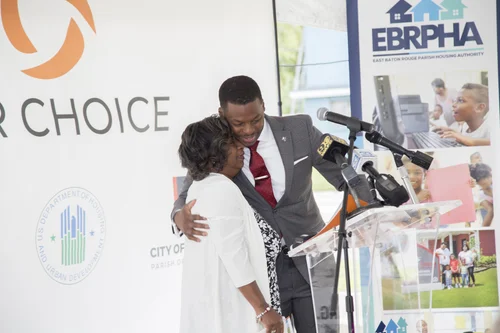 Man in suit hugs woman at podium with BR Choice and EBRPHA logos in background.
