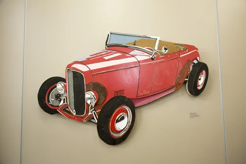 Wall-mounted artwork of a classic red hot rod convertible.