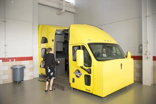 Yellow Kenworth T700 semi-truck cab training simulator in the workshop.