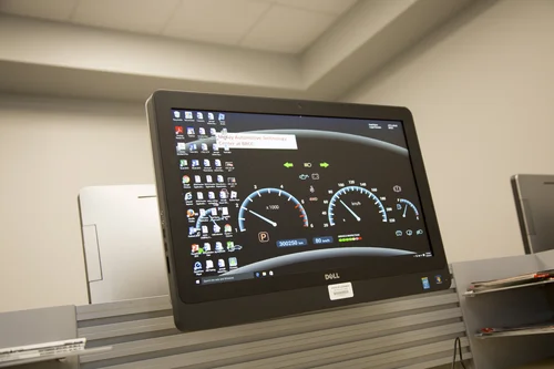 Computer monitor displaying a digital car dashboard wallpaper.