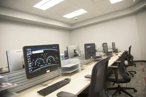 Rows of computers in a classroom displaying digital car dashboard wallpapers.