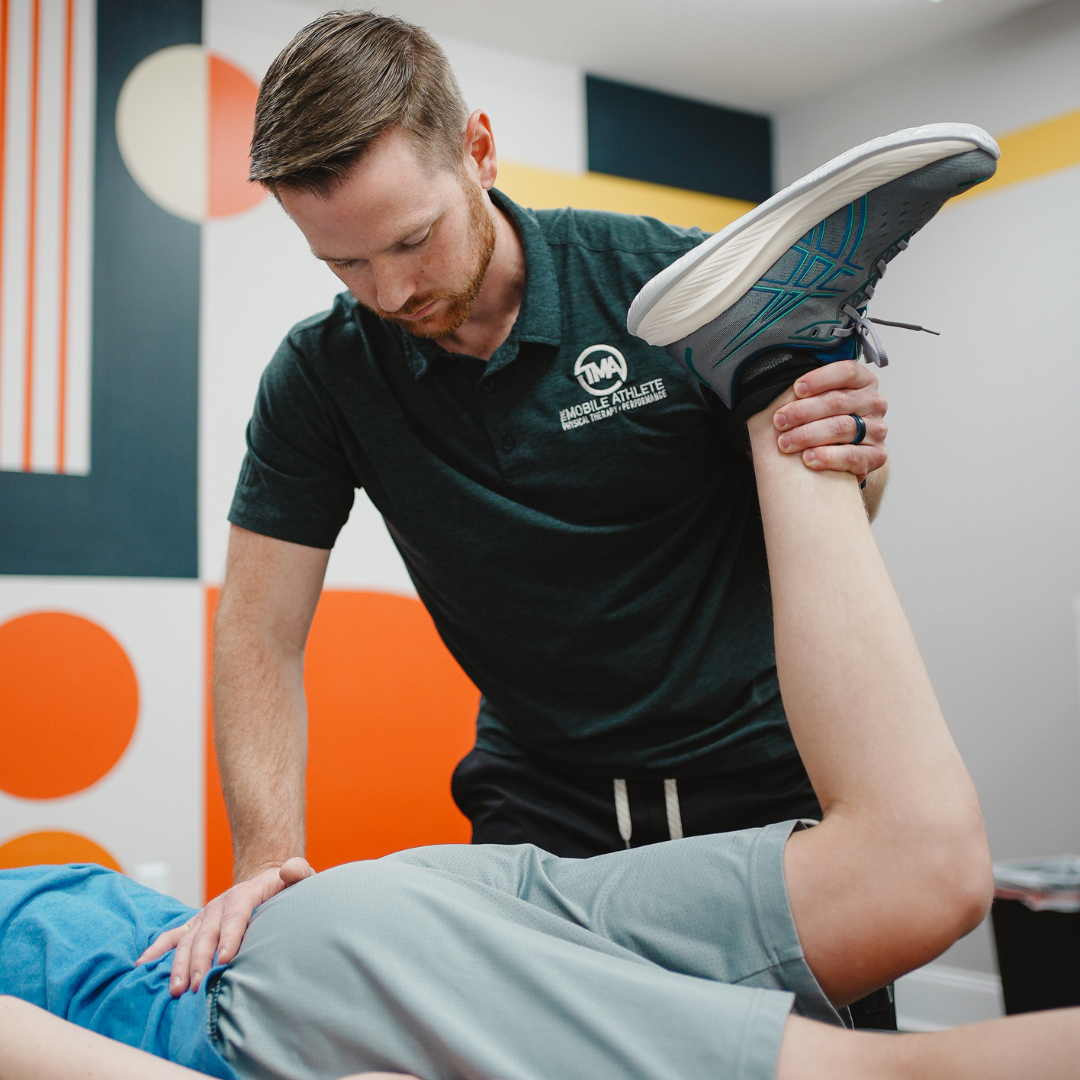Physical therapist assisting a patient with a leg stretch in a therapy room.