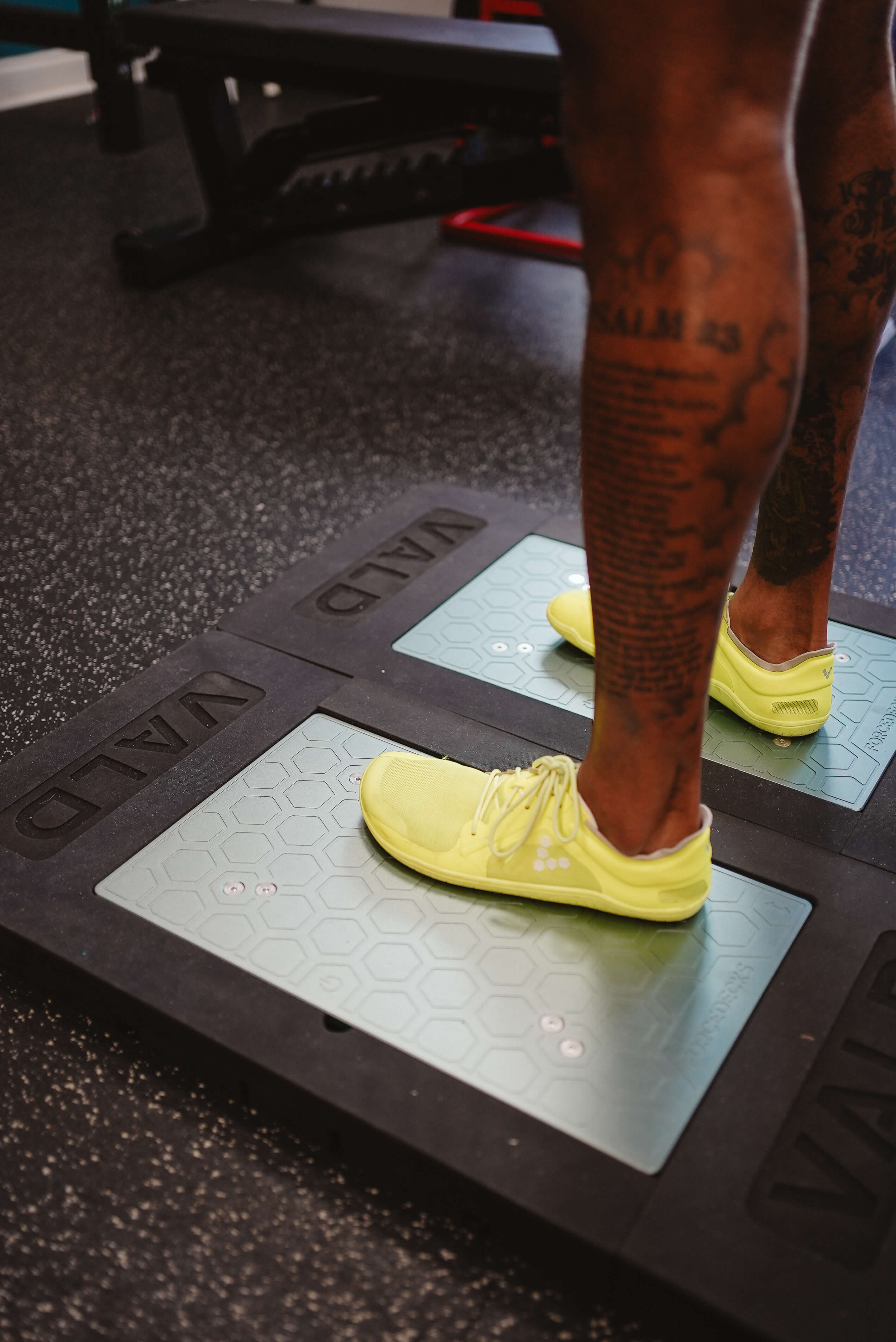 Person wearing yellow shoes standing on VALD force plates in a gym.