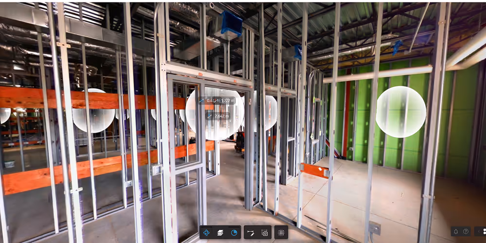 Interior view of a commercial building under construction with metal framing and exposed pipes.