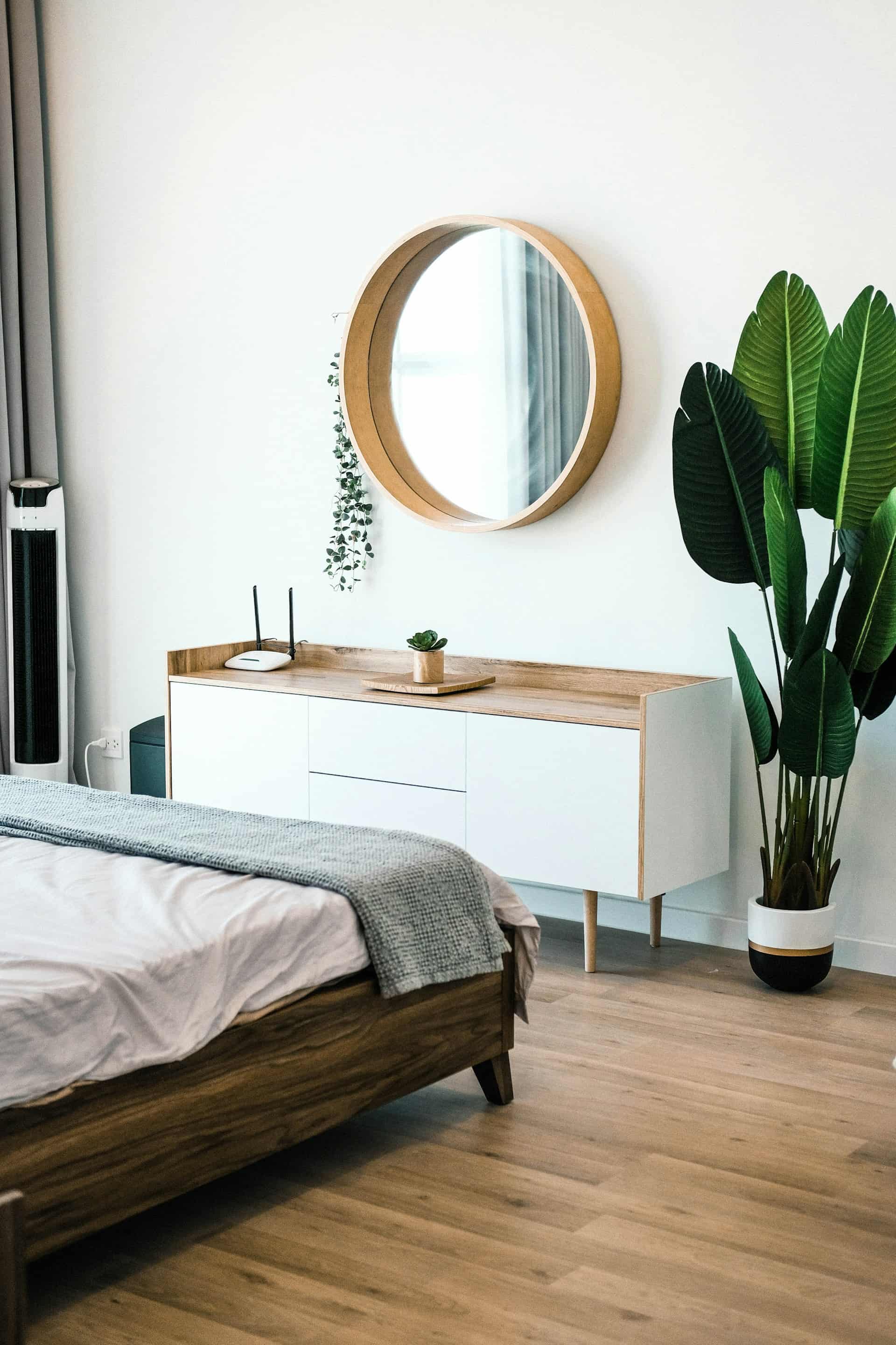 Modern bathroom with glass shower enclosure, bathtub with black fixtures, gray cabinetry, large mirror, and decorative dried flowers on the counter.