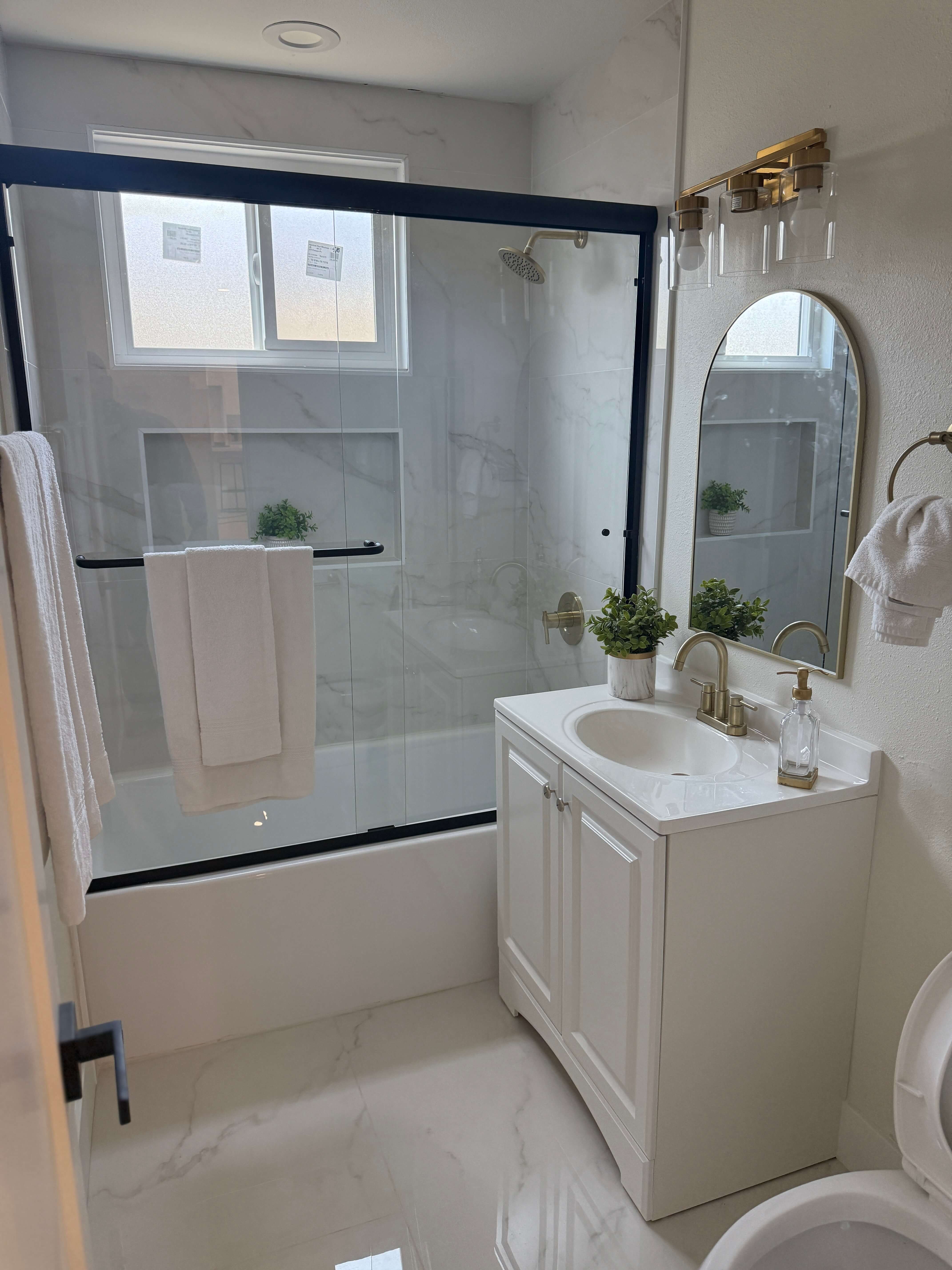 Modern kitchen with white hexagonal tile backsplash, white cabinets with leather handles, a large stainless steel stove, and a marble island.