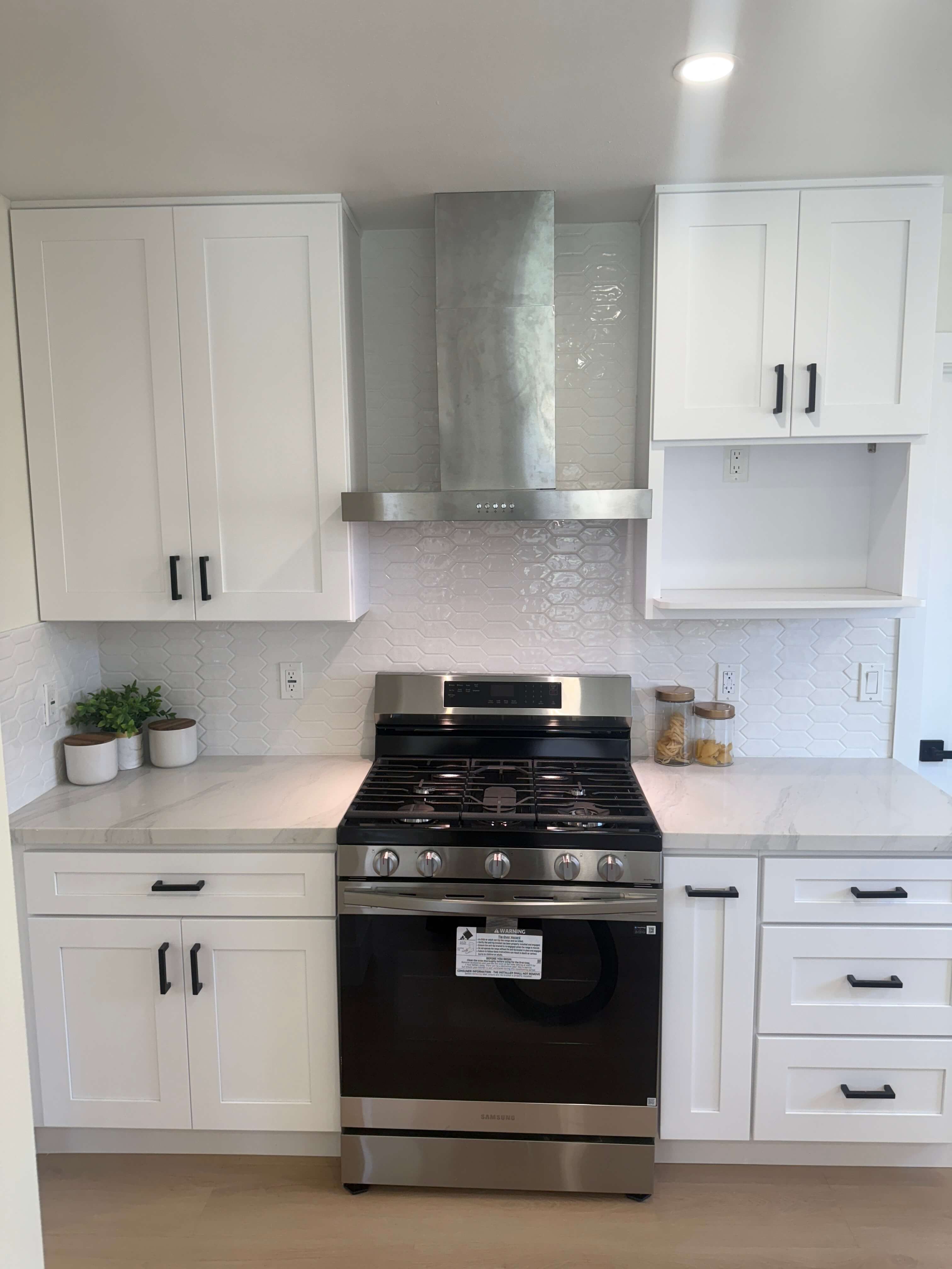 Interior of a house under construction showing exposed wooden framing, ceiling joists, stacked wood planks, and a fireplace.