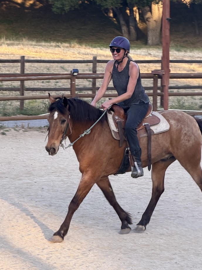 Adult beginner practicing posting trot in a lesson