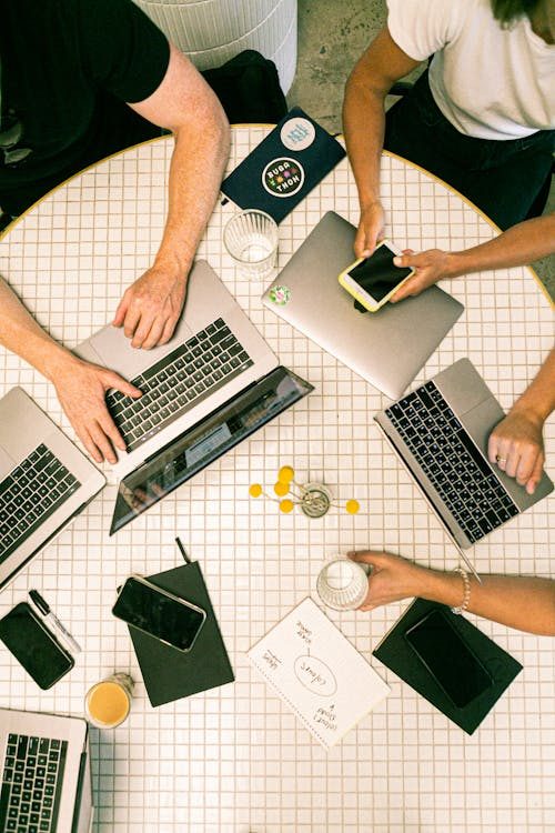 Top view of a team collaborating with laptops, phones, and notes in a modern office