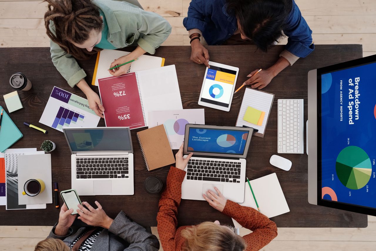 A diverse team collaborating on digital marketing strategies at a desk, using laptops and tablets. 