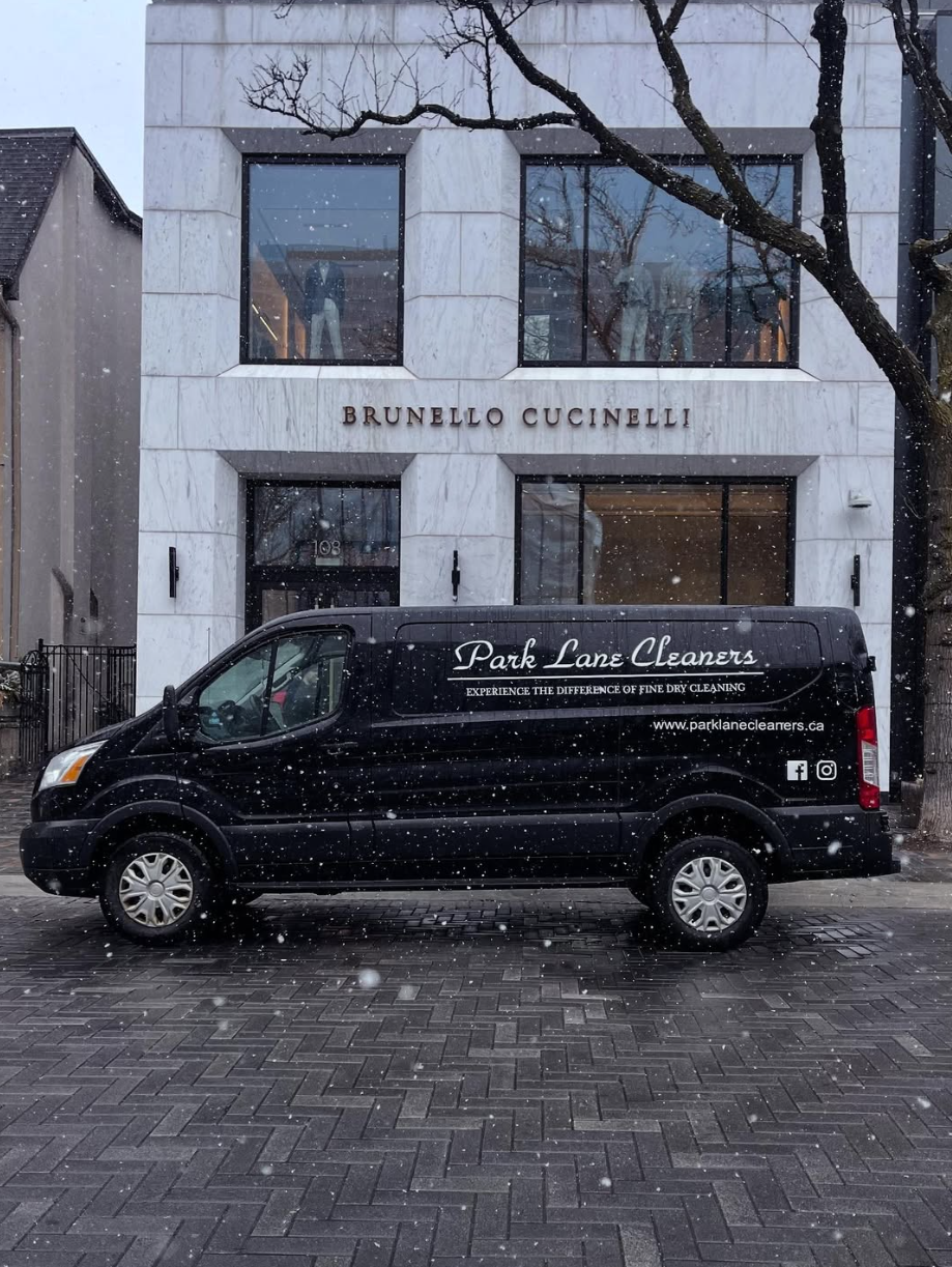 Black Park Lane Cleaners delivery van parked in front of a Brunello Cucinelli store on a snowy day.