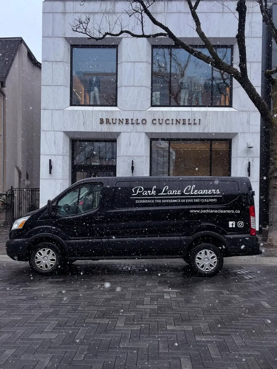 Black Park Lane Cleaners delivery van parked in front of a Brunello Cucinelli store on a snowy day.