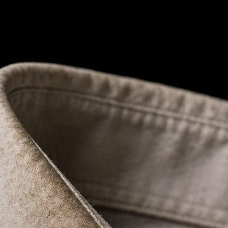 Close-up of a pressed beige shirt collar against a dark background