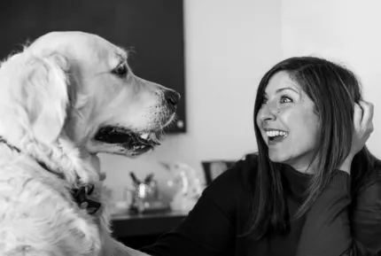 A beautiful smiling brunette woman playing with a golden retriever at the best creative marketing agency’s office.