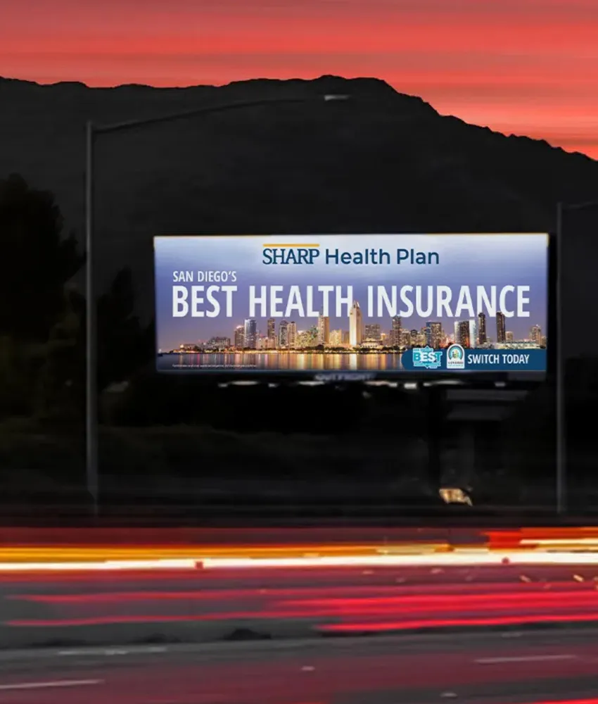 A billboard with a city skyline designed by a top creative marketing agency in San Diego in front of dark mountains and a pink sunset.
