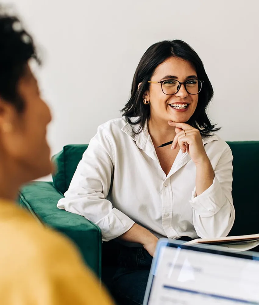 A beautiful Hispanic woman wearing glasses and a white collared shirt in a leadership meeting.