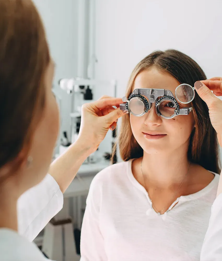 A Caucasian girl getting an eye exam from a female optometrist. 