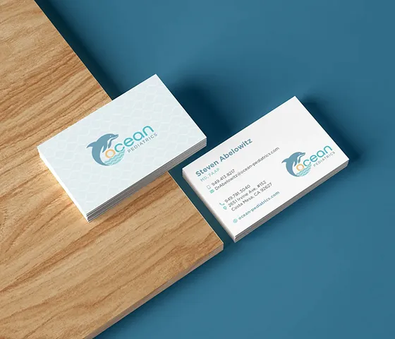 Ocean Pediatrics’ business cards on a desk in stacks showing both the top and the bottom, designed by one of the best creative marketing agencies. 