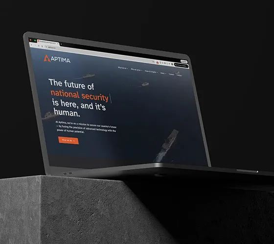 A laptop on a stone countertop open to the new Aptima website designed by one of the best creative and digital marketing agencies. 
