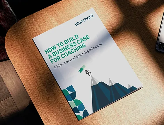 Wood desk with a printed page of an eBook on top featuring a graphic of a man at the top of a mountain, created by a top creative marketing agency.