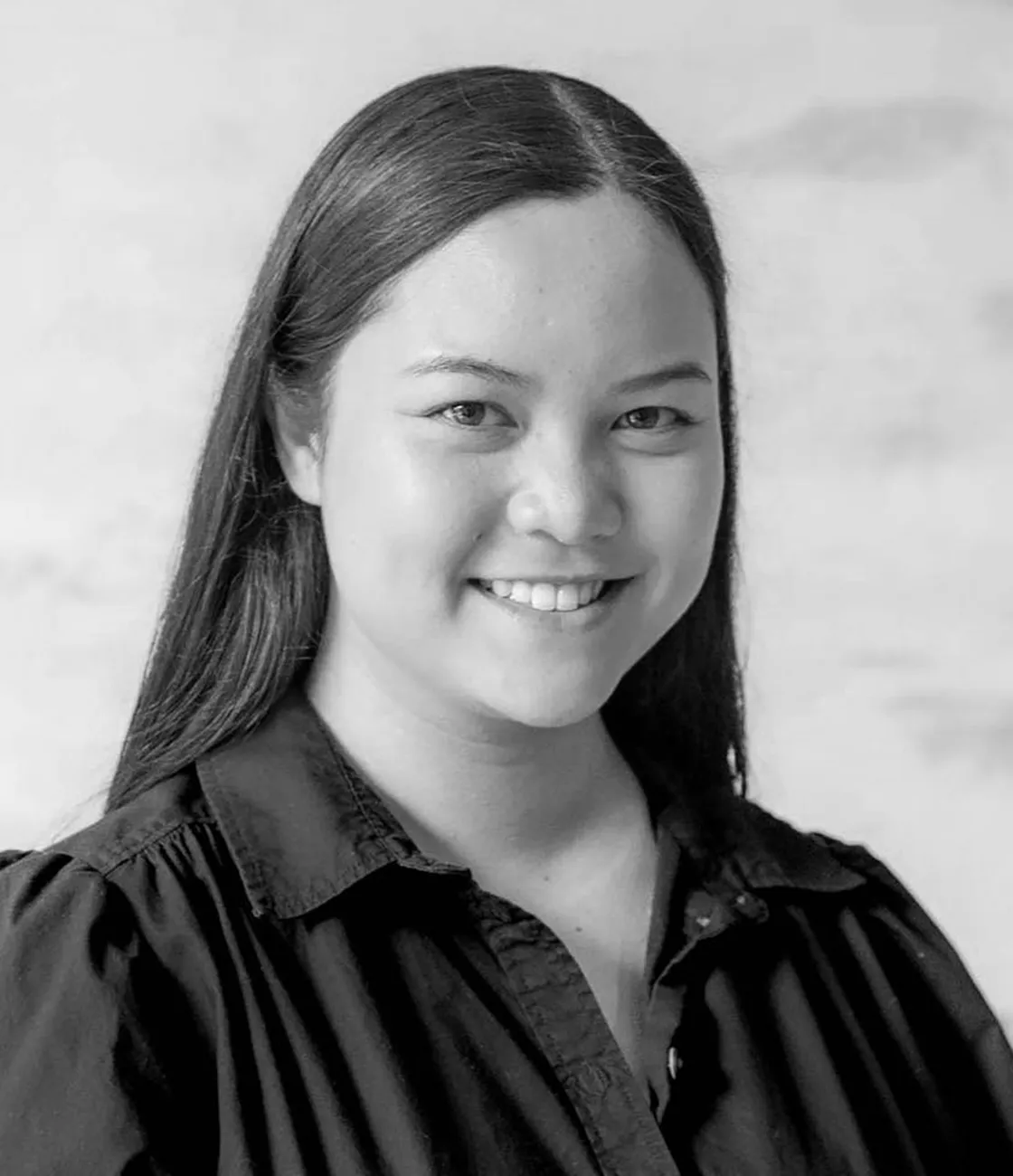 A beautiful Asian female social media marketing professional with long black hair smiling.