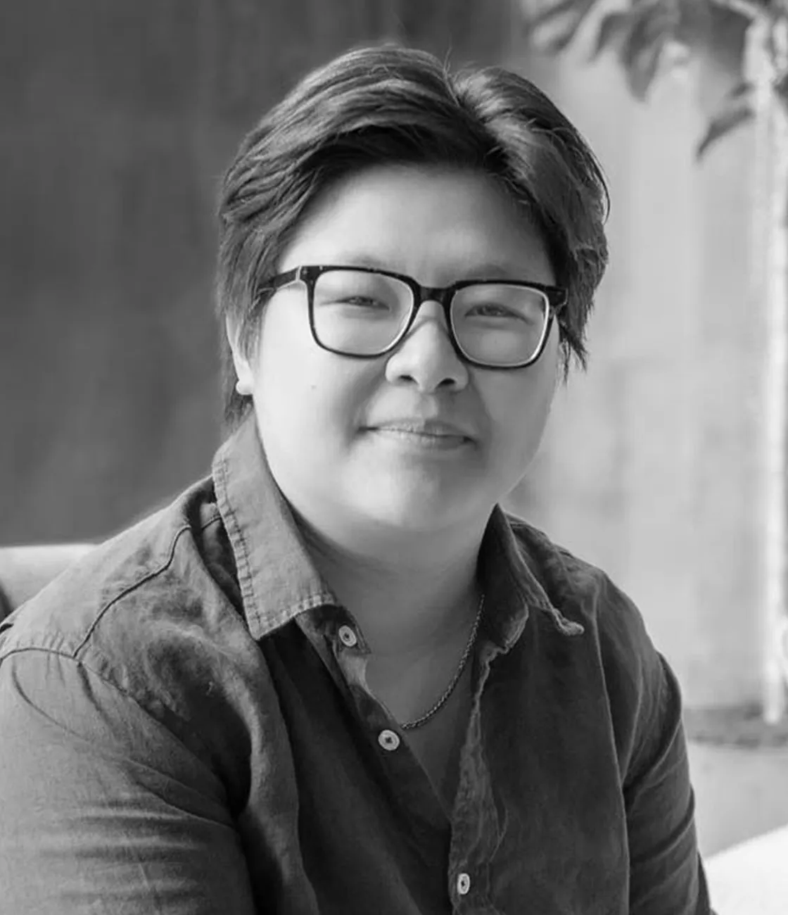 A beautiful Asian female graphic designer with short black hair wearing glasses and smiling.