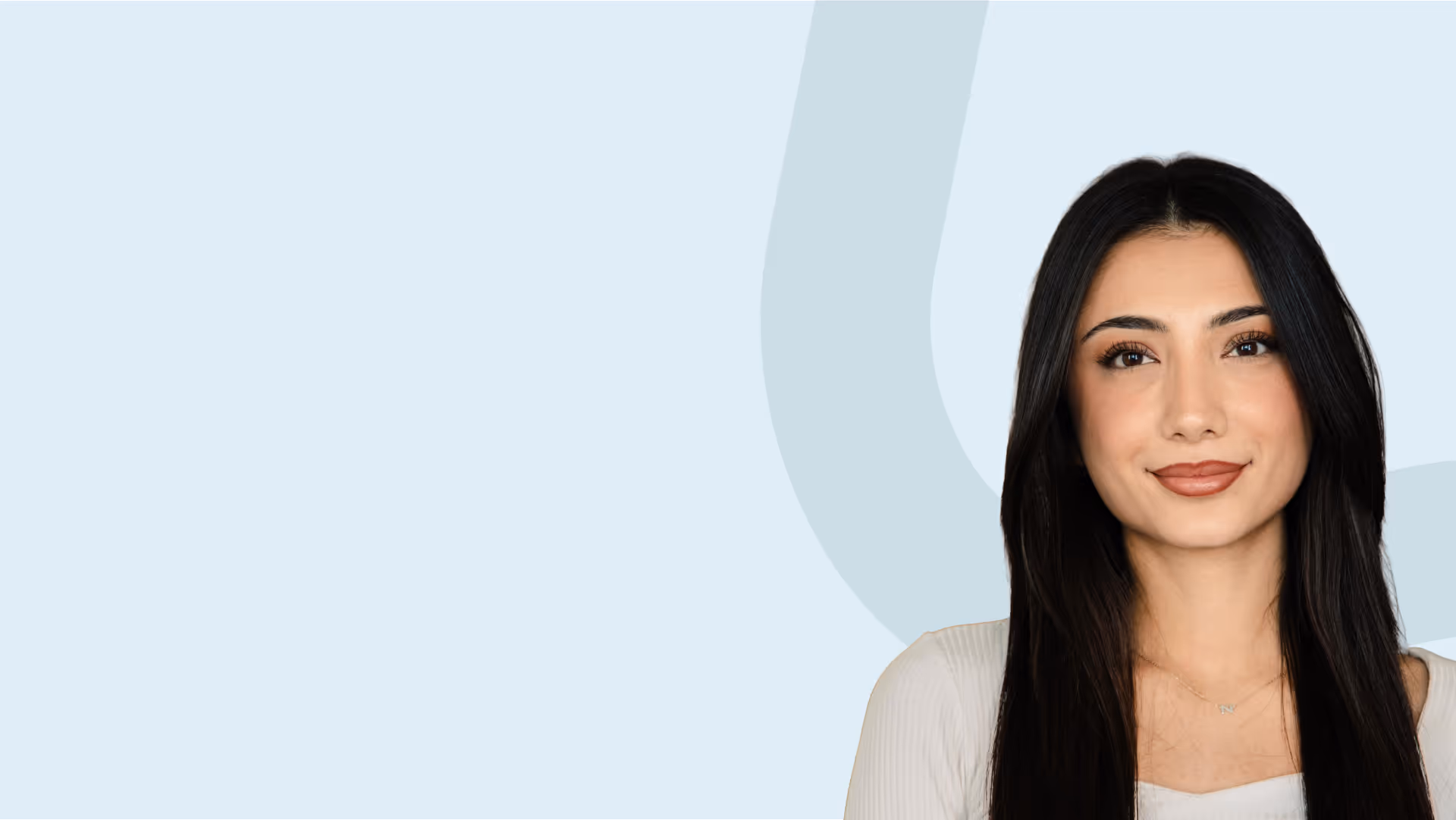 Porträt einer jungen Frau mit langen schwarzen Haaren vor hellem Hintergrund.