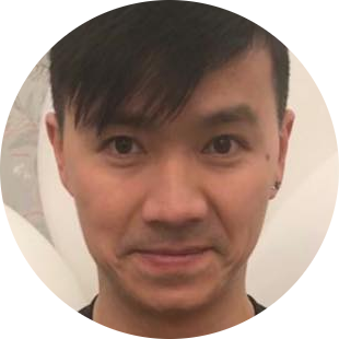 Close-up of a man with short black hair and dark eyes smiling slightly.