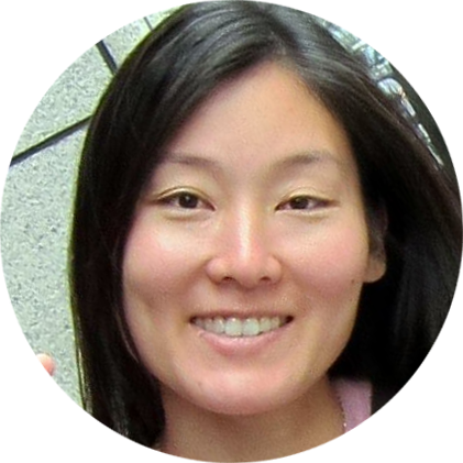 Close-up of a smiling woman with long black hair against a gray textured background.