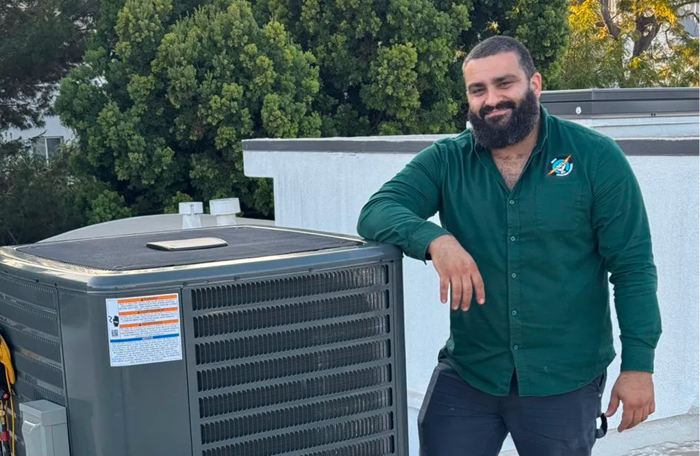 HVAC technician standing next to HVAC System