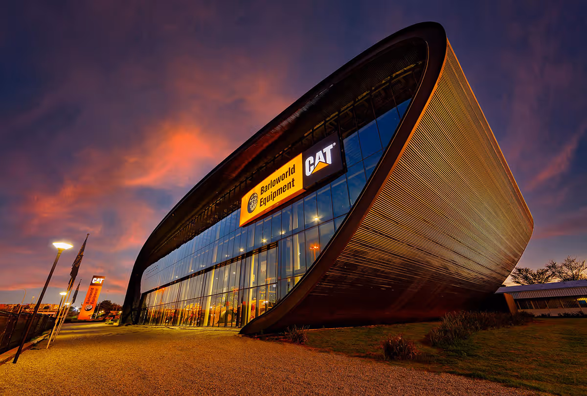 Modern Barloworld Equipment building with curved architecture and large glass facade at sunset.