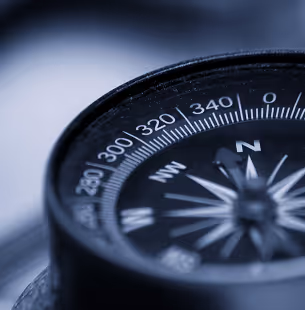 Orange sports car drifting on a race track kicking up a cloud of dust.