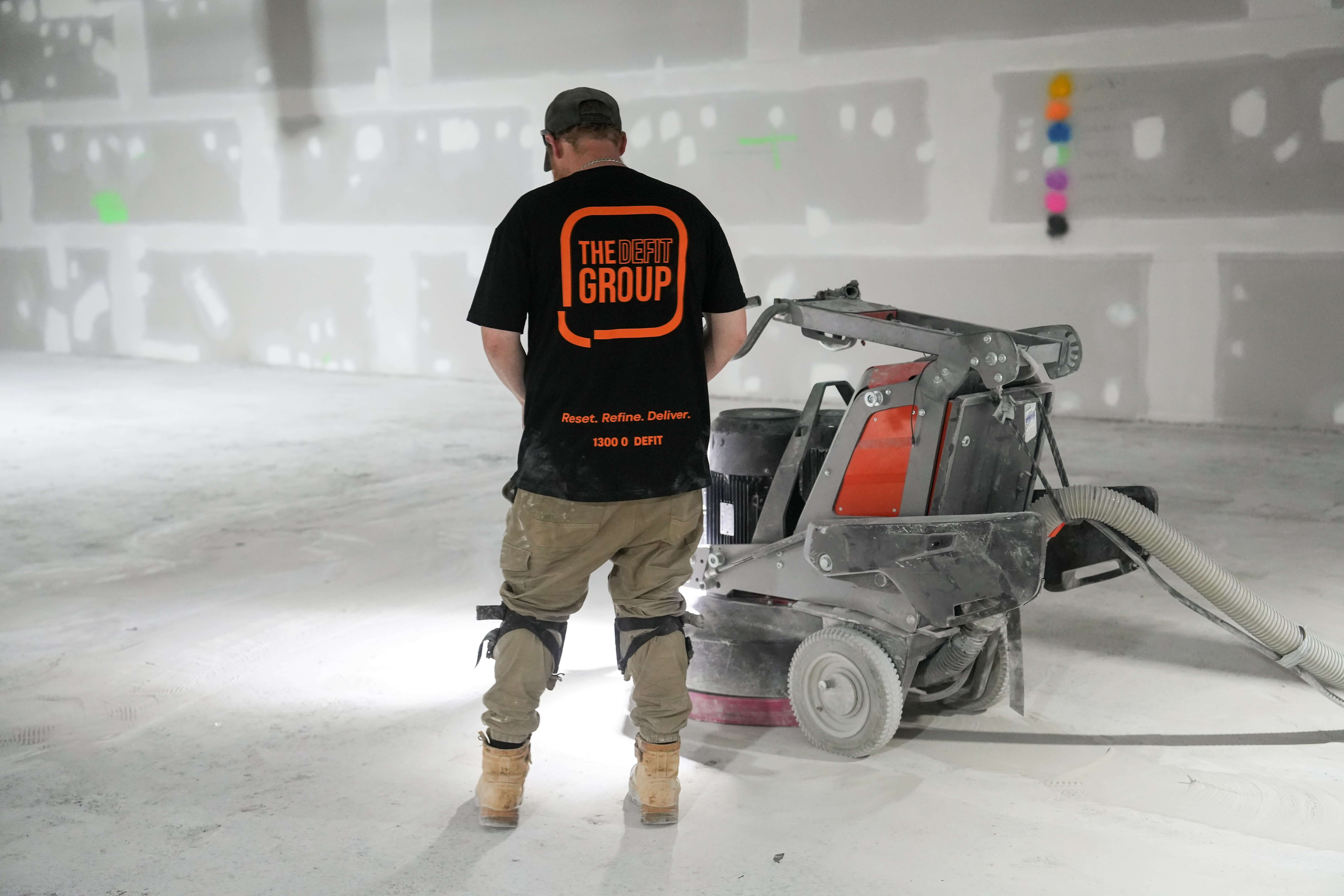 Large empty indoor space with multiple square columns and fluorescent ceiling lights.