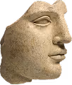 Stone sculpture of a human face in profile with closed eyes and a serene expression.
