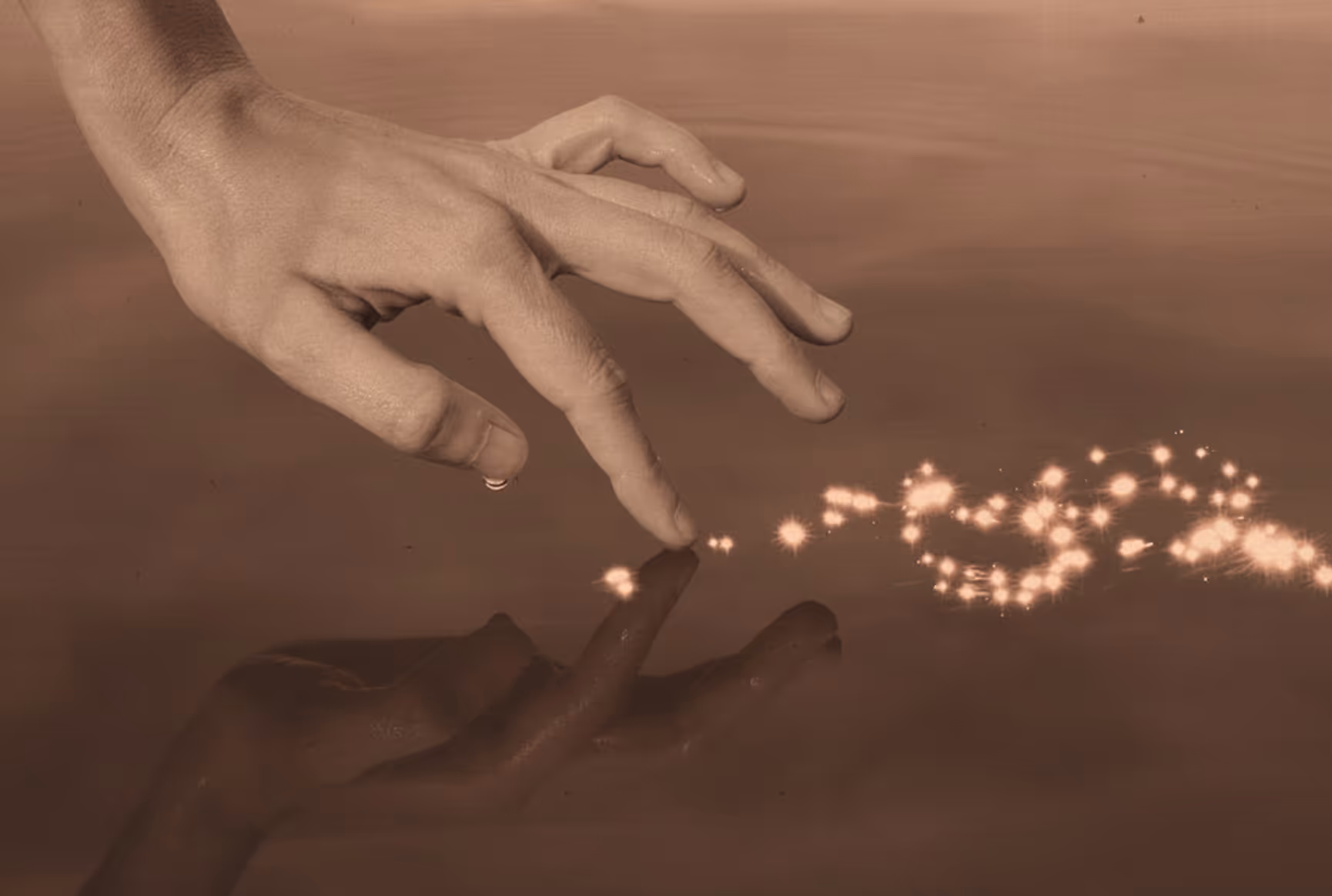 Hand with fingers touching water surface creating sparkling light reflections.