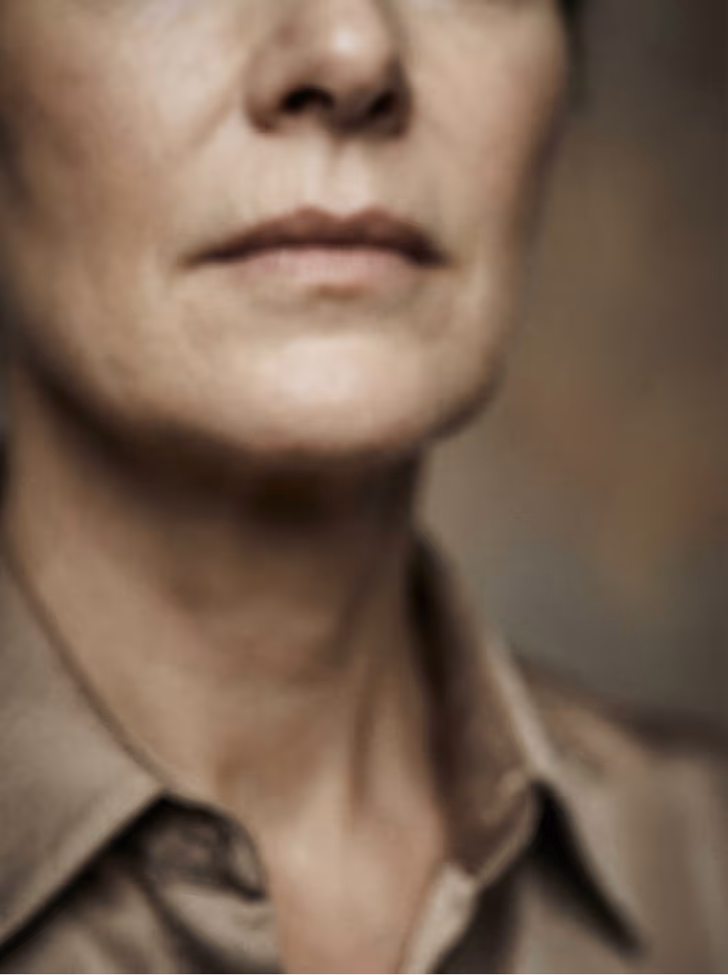 Close-up of a person's lower face and neck wearing a beige collared shirt.
