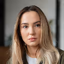 Portrait of a woman with long blonde hair and light makeup looking slightly to the side.