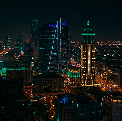 مشهد ليلي لمدينة الرياض يعرض برج الفيصلية وبرج المملكة مضاءين بأضواء ملونة وزينة المدينة في الخلفية.