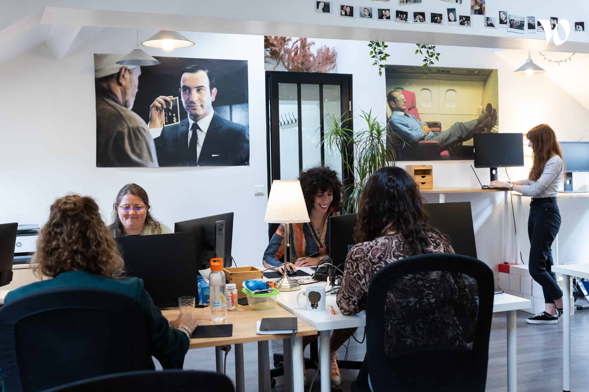 Personnes travaillant dans un bureau partagé moderne avec des posters de films et une lampe sur une table.
