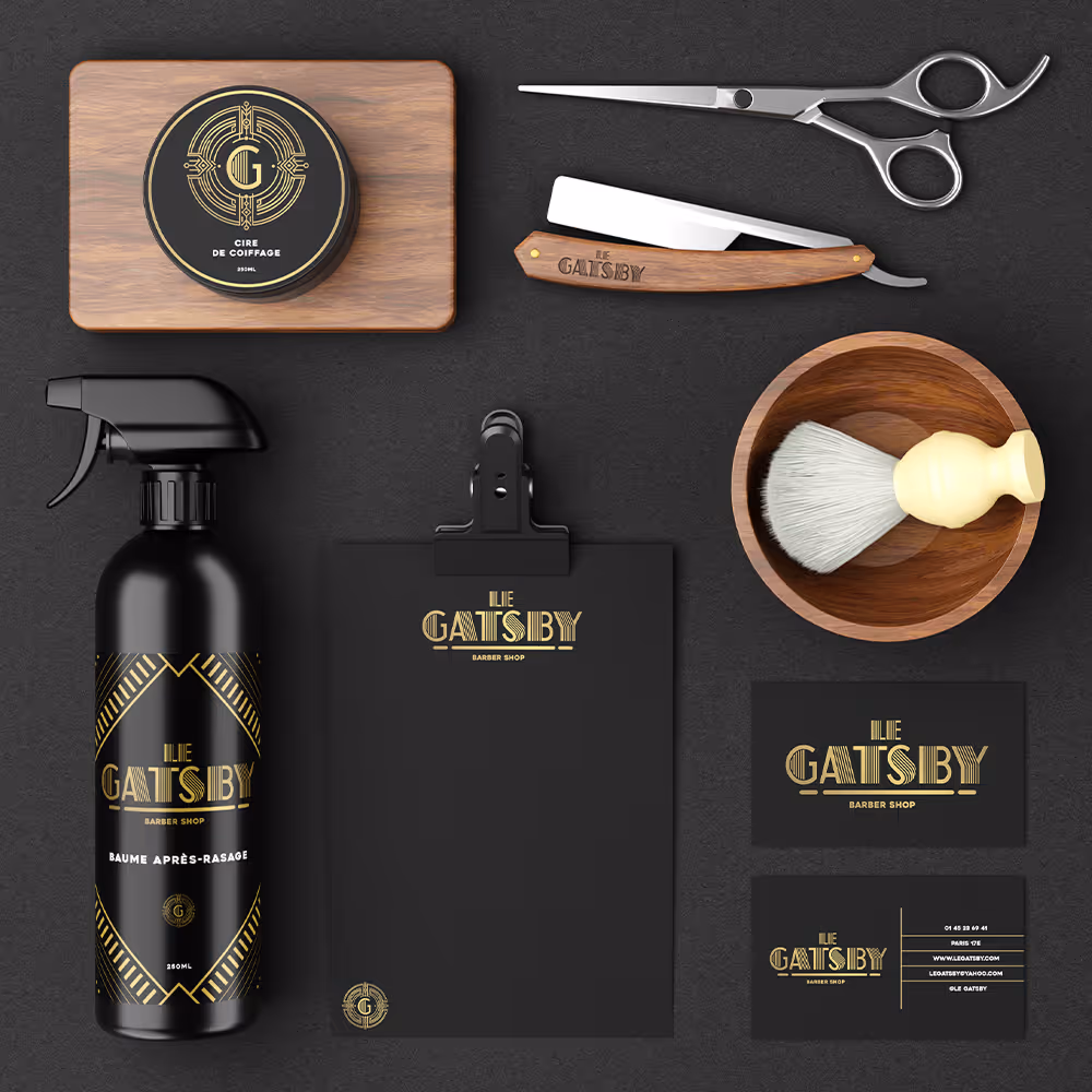 Barber shop branding set including pomade tin, straight razor, scissors, spray bottle, shaving brush with bowl, clipboard, and business cards with gold and black art deco design.