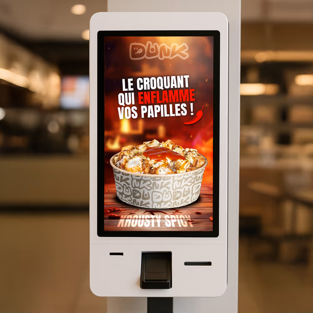 Self-service kiosk screen showing a spicy popcorn snack with the text in French, 'Le croquant qui enflamme vos papilles!' and a red chili pepper icon.