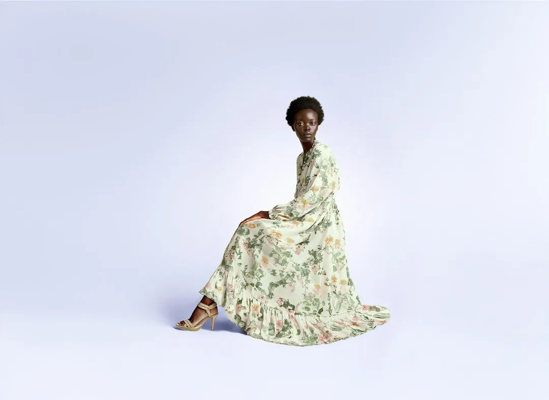 A woman wearing a flowered dress sits on a blue background.