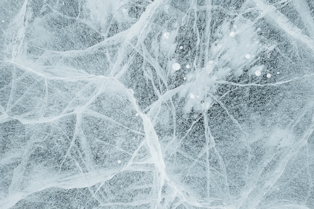Close-up view of translucent ice with visible cracks and air bubbles trapped inside.