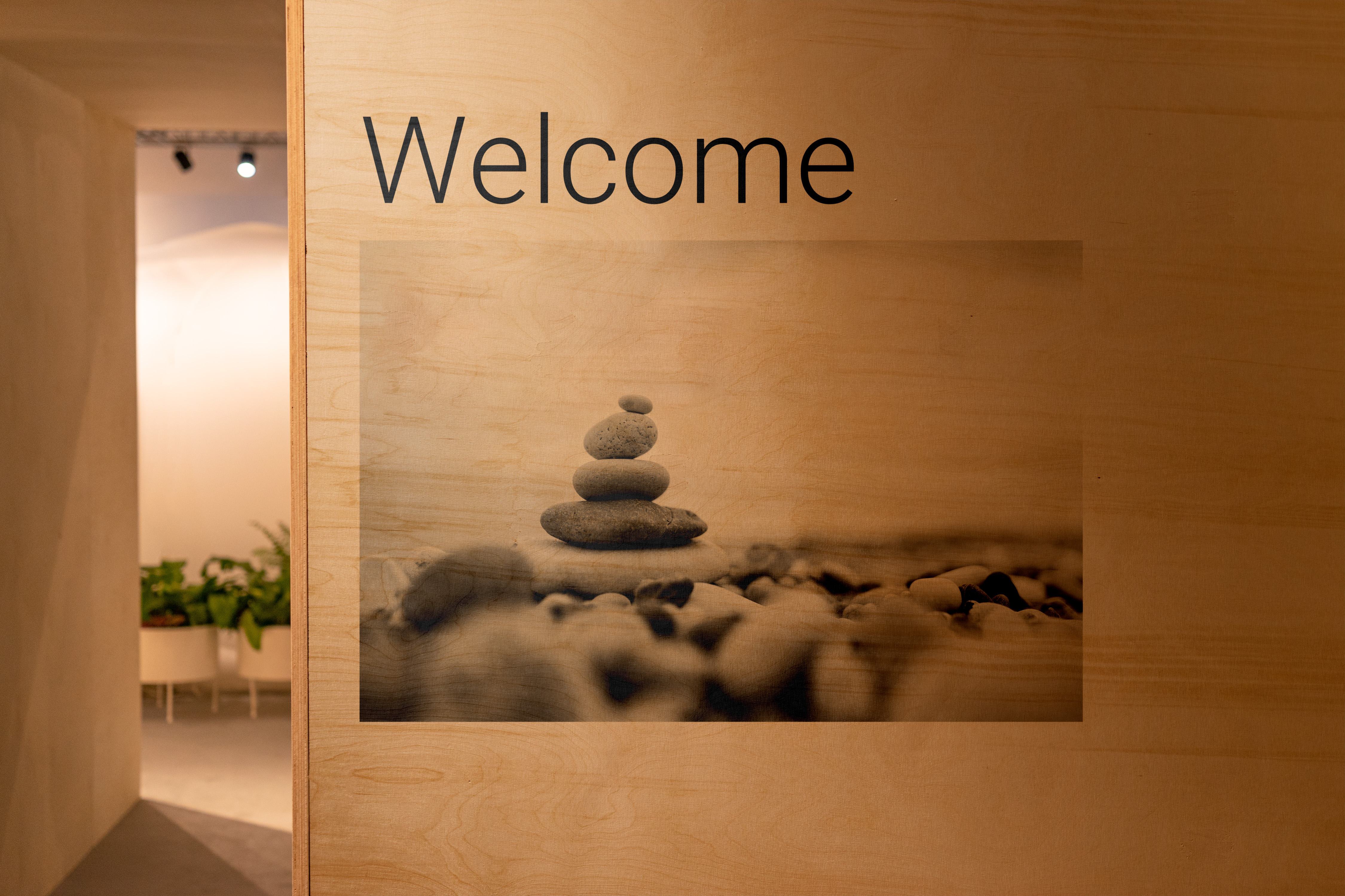 Tre stabler balanserer oppå hverandre på en steinete overflate under teksten Velkommen på en lys trevegg.