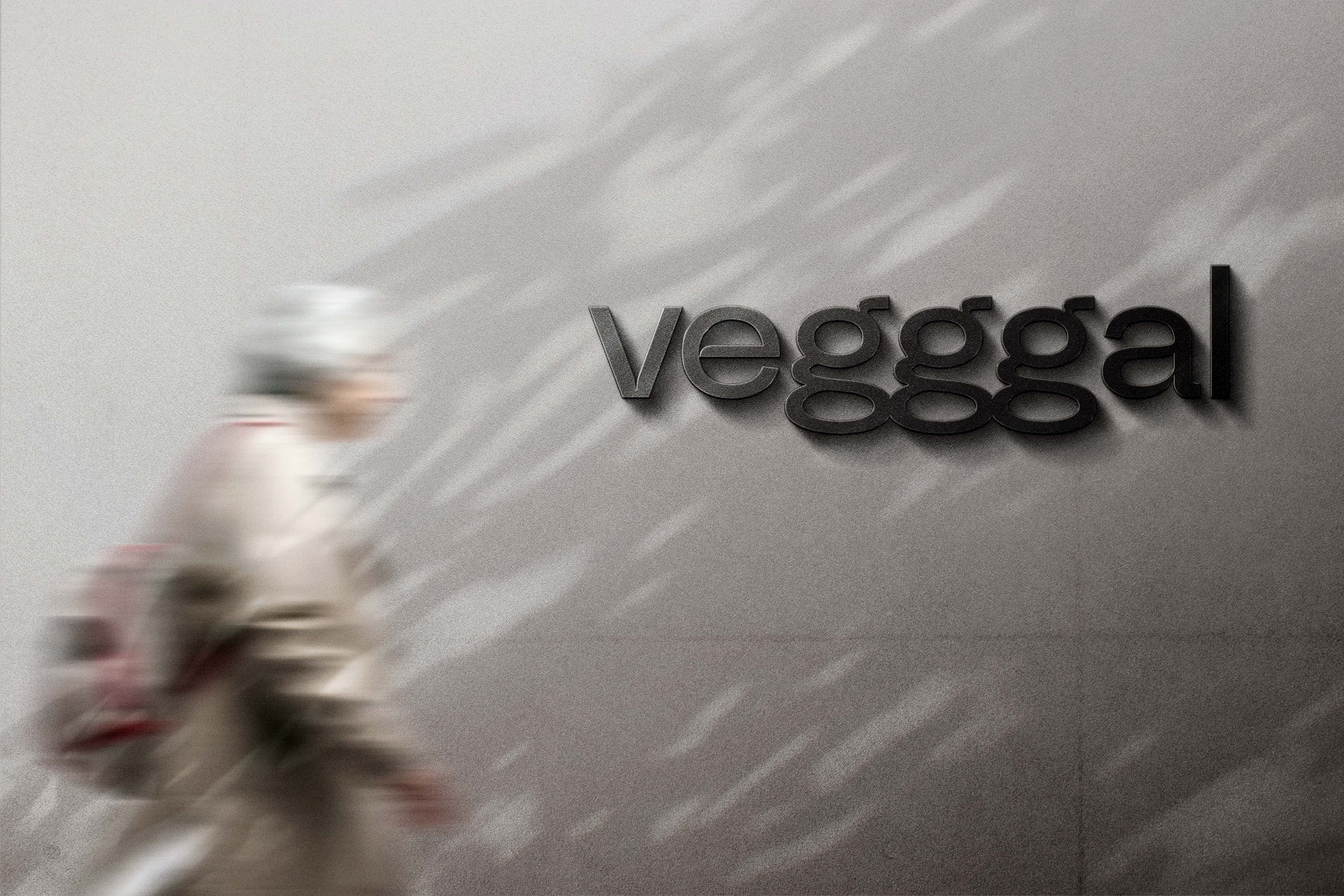 En uskarp eldre person med ryggsekk går forbi en vegg med teksten «vegggal».