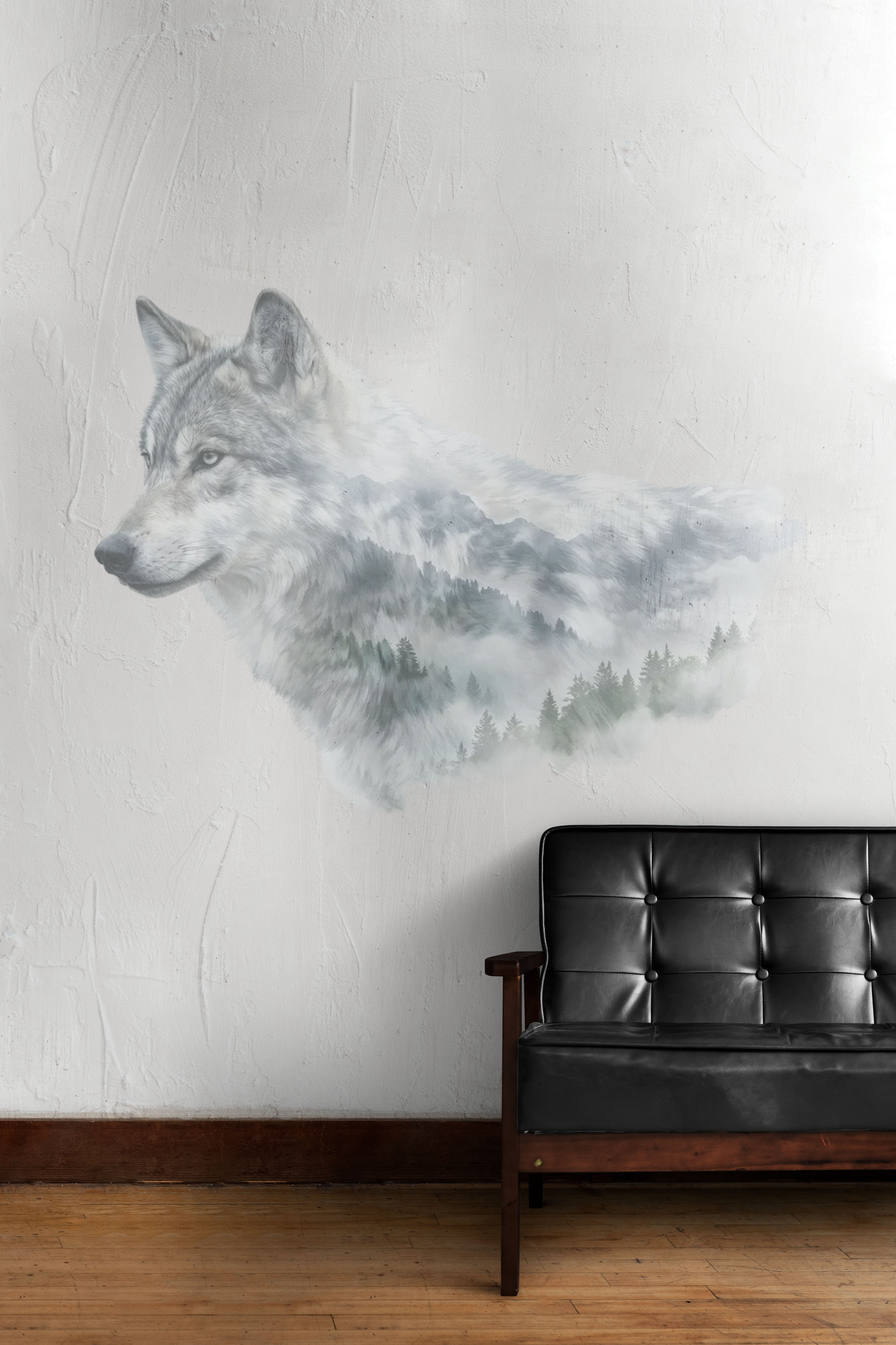 Veggkunst som viser hodet til en ulv med et tåkelagt furuskogbilde innebygd, over en svart skinnsofa med trearmstøtte.